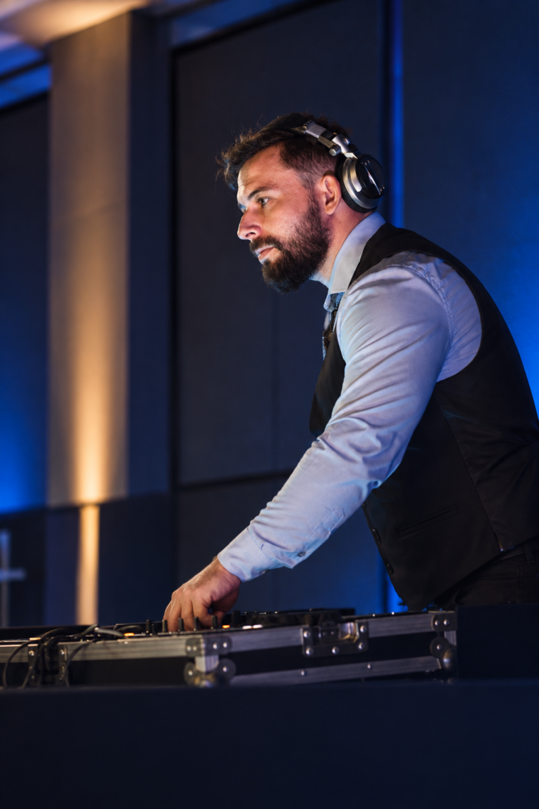 DJ Andrez com fones e traje social nos equipamentos