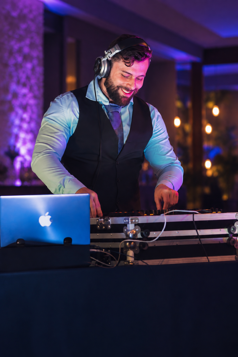 DJ Andrez de colete e gravata operando a controladora